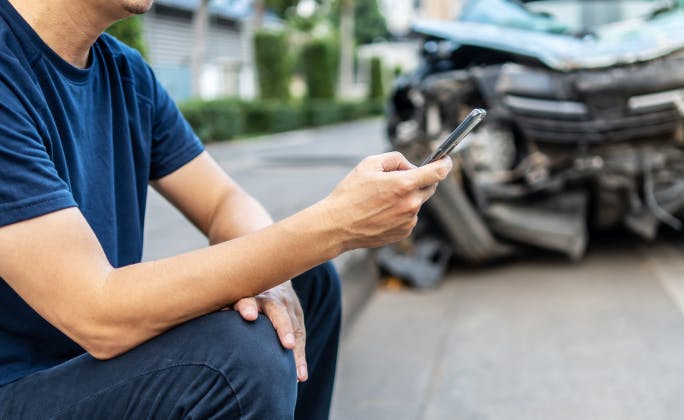 Conductor gestionando un siniestro de coche desde el móvil