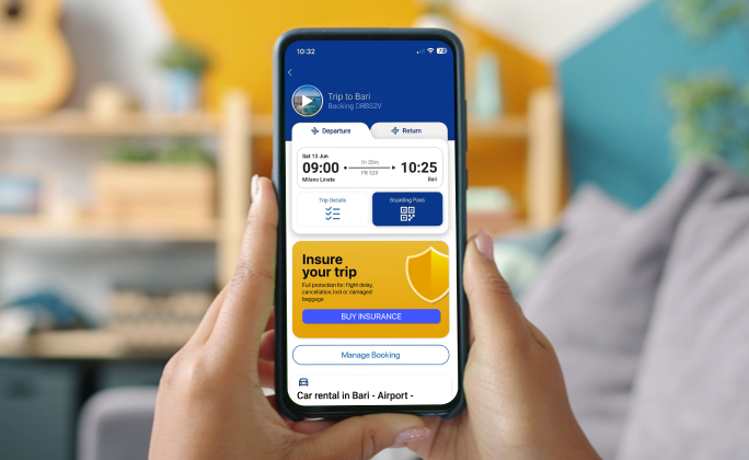 Smartphone che mostra una prenotazione ferroviaria per Bari con un'offerta di assicurazione di viaggio integrata.