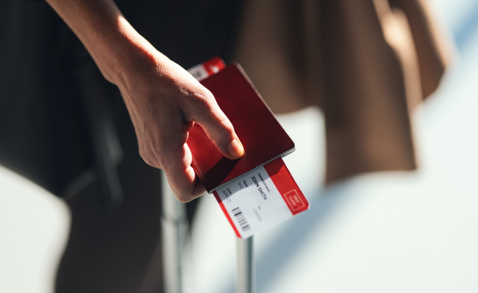 Mano de una persona sosteniendo un pasaporte y una tarjeta de embarque