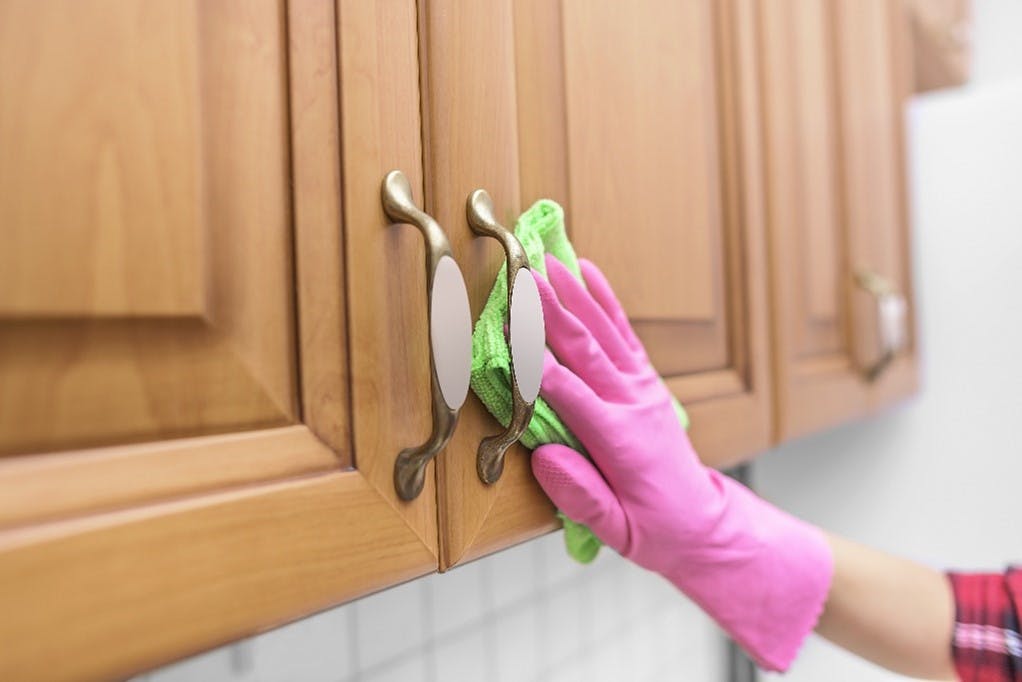 wiping a kitchen cabinet 