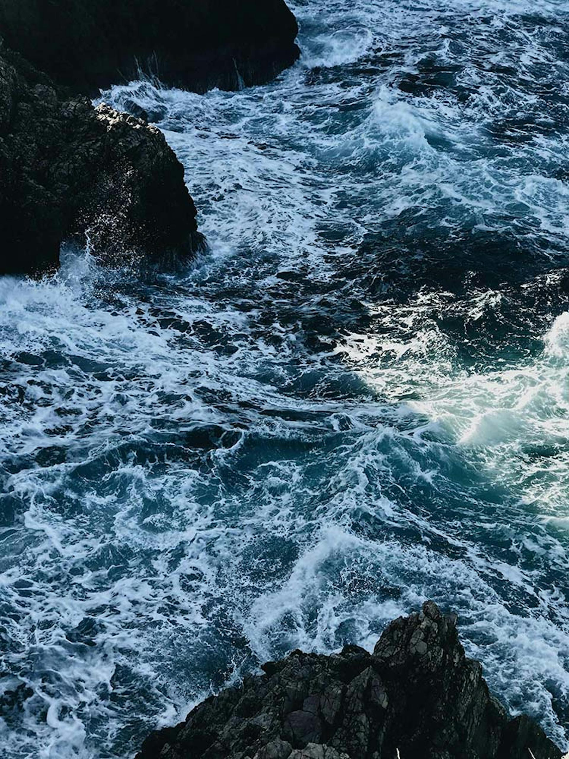 Photograph of waves breaking against rocks