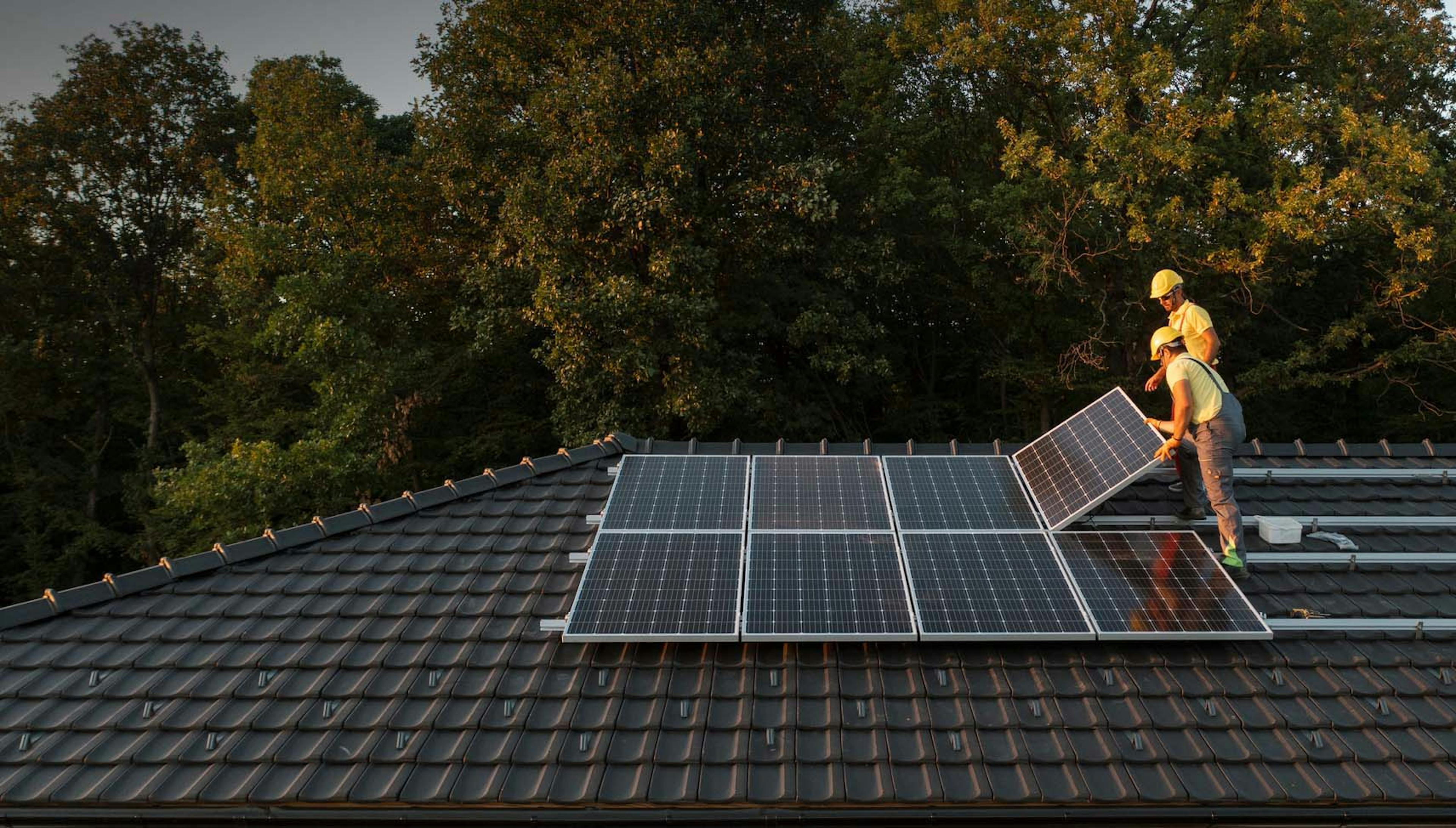 Photograph of workers installing solar panels on a roof