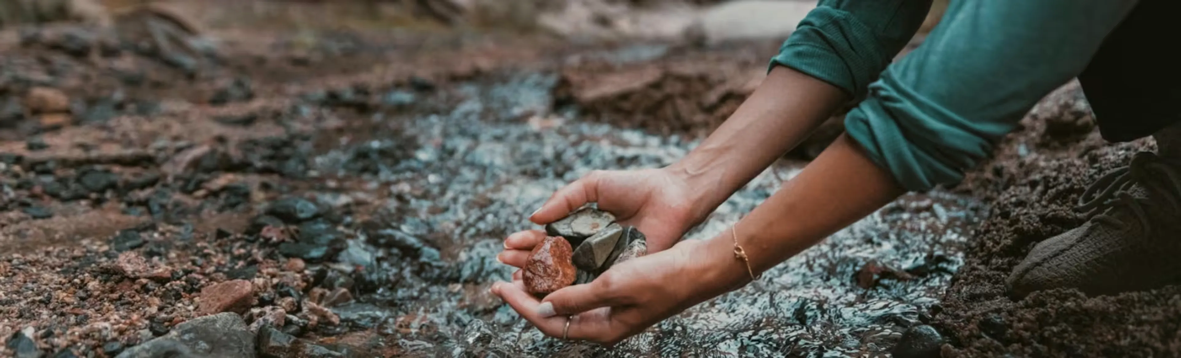Hands cupping stones in a riverbed