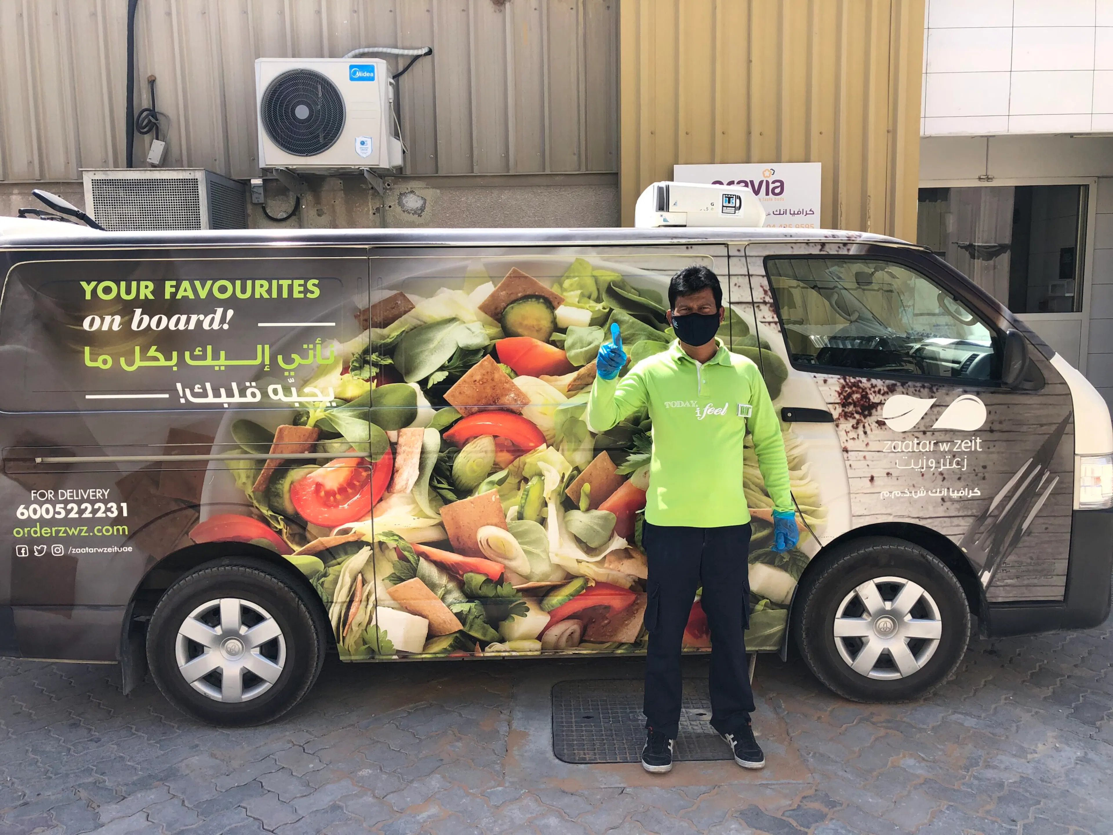 A Cravia delivery driver standing beside a Zaatar w Zeit branded van
