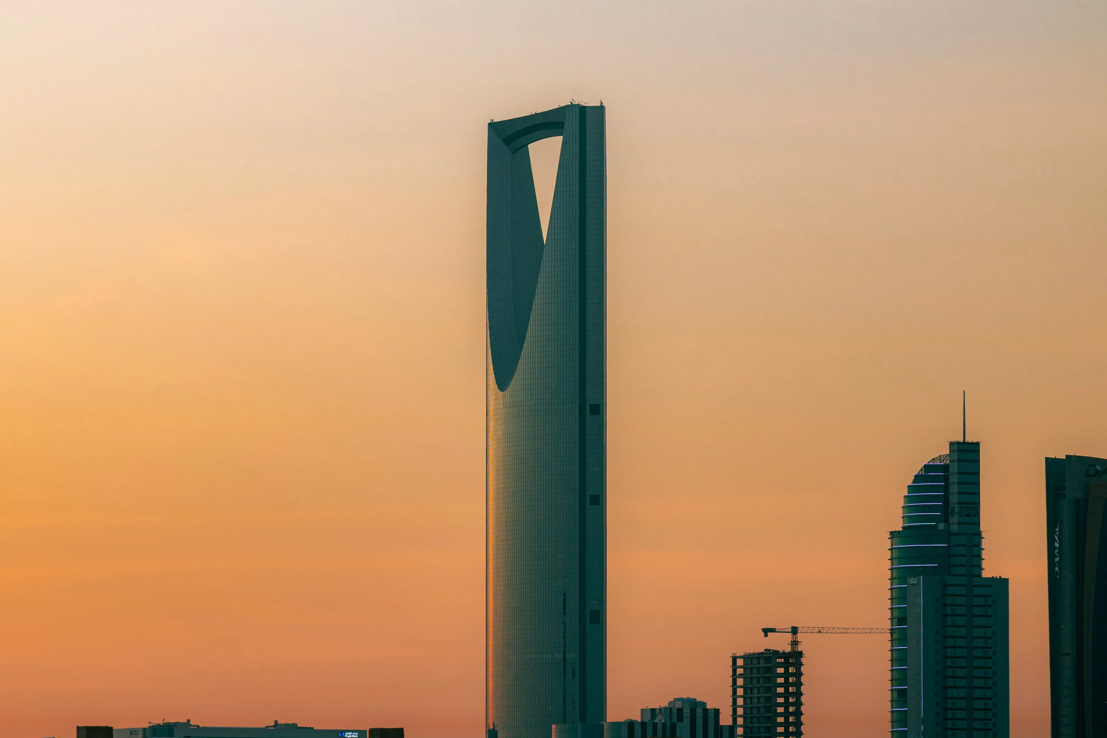 The Kingdom Centre skyscraper against a warm orange sky in Riyadh, Saudi Arabia