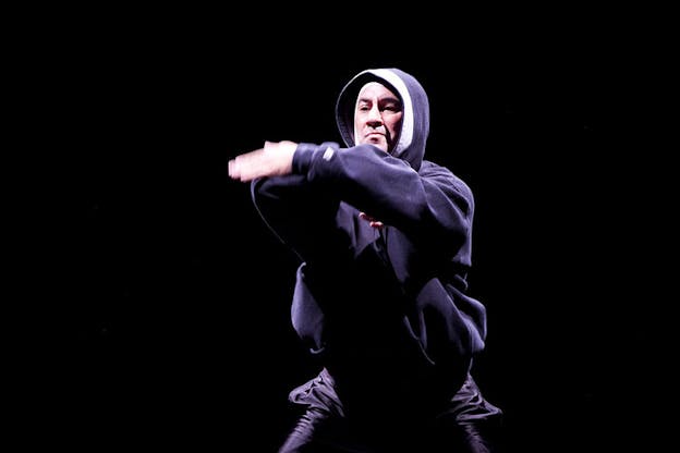 Figure clad in a navy blue hoodie moves his arms in front of him.