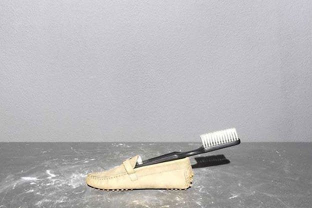 Close-up of a toothbrush placed inside a beige loafer. 