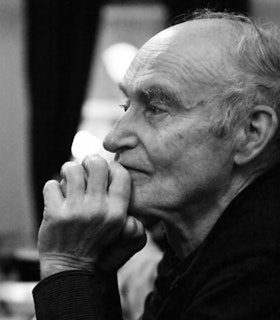 A black-and-white photograph of Christian Wolff, in profile with his hand on his chin.
