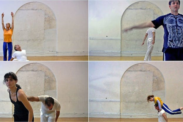 Four-frame still of performers in pedestrian clothing performing various motions against a stone wall background. 