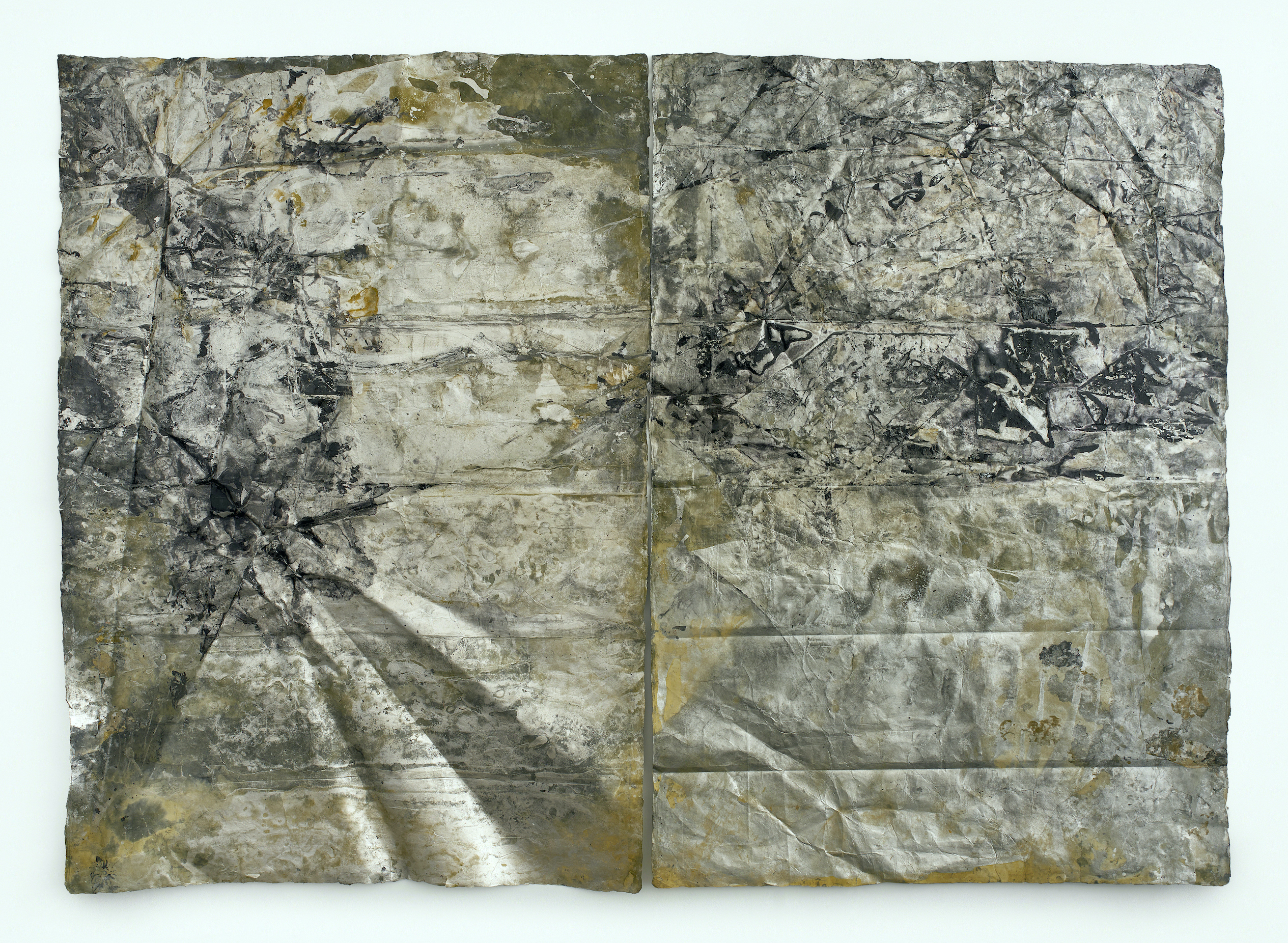 Two panels of paper that have been slightly crumpled, folded, and wrinkled, painted with mottled black, white, gold, and silver.
