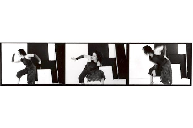 A triptych of black and white photographs of a performer wearing all dark clothes in front of a geometric black and white background. On the far left, they bend their front leg and hold their arms at 90 degree angles. In the middle image, they lean forward and hold out their arms behind them. In the far right image, they lean foward and hold their lower back with their arm. 