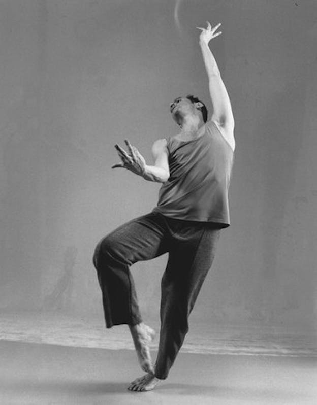 A performer conducts a move in which their knee is bent in the front while the other leg supports their body and one arm extended upwards while the other in the front. 