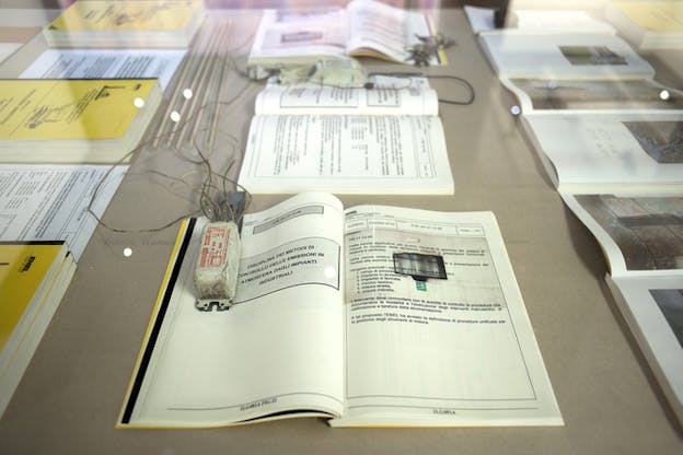 Open books in a surface with burn marks and small devices with cables connected to their surfaces.