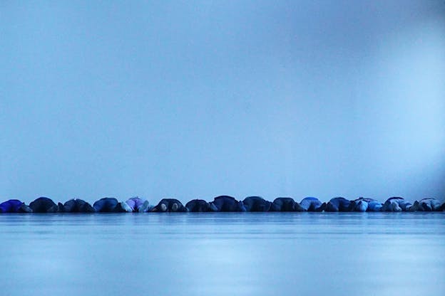 Image of the soles of people laying down on the floor in a line a line.