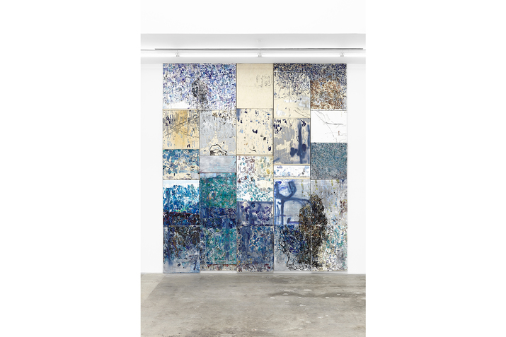 A collage of rectangular abstract paintings with blue hues put together on a wall.