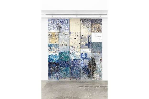 A collage of rectangular abstract paintings with blue hues put together on a wall.