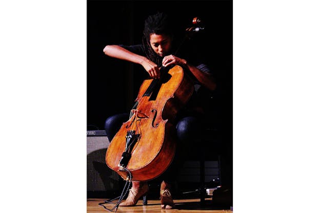 Photograph of Tomeka Reid playing the cello on stage.