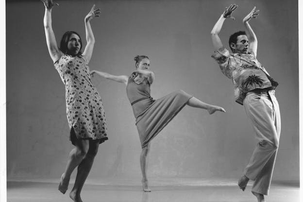 An image of three performers executing dance moves. Two performers have their hands upwards in clawed shapes, the third in between them further back raises their leg forward.