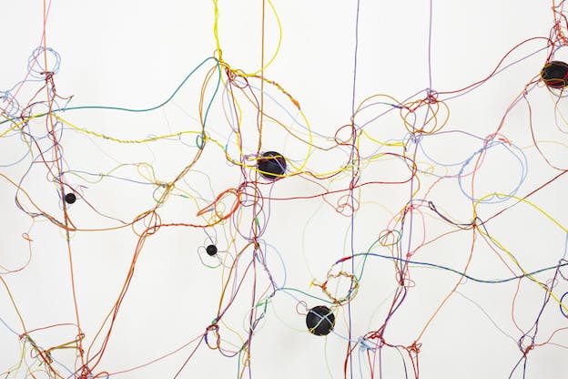 Colorful tangled cords on a white background holding black circle button-like pieces in various areas.