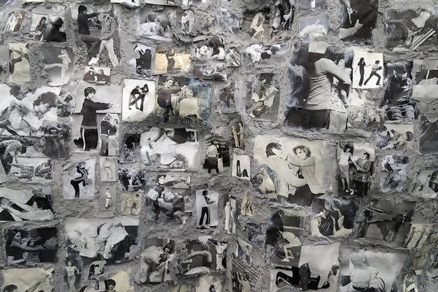 A collage of black and white photos on a textured gray wall. The photos show figures in various fighting stances.