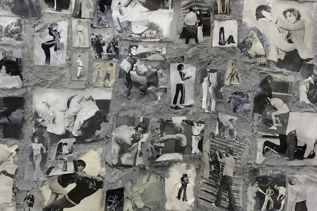 A collage of black and white photos on a textured gray wall. The photos show figures in various fighting stances.