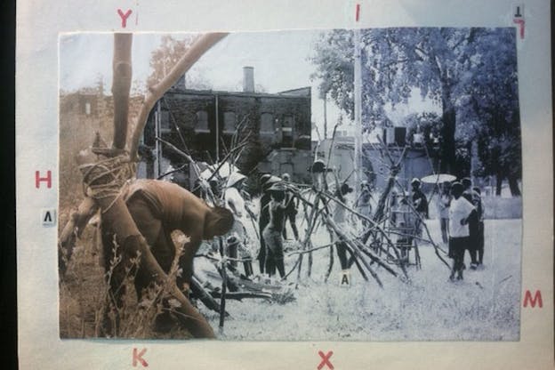 A sepia photograph and a black and white photograph both depicting persons in a grassy yard piling sticks juxtaposed together on a sheet of paper with red floating letters.