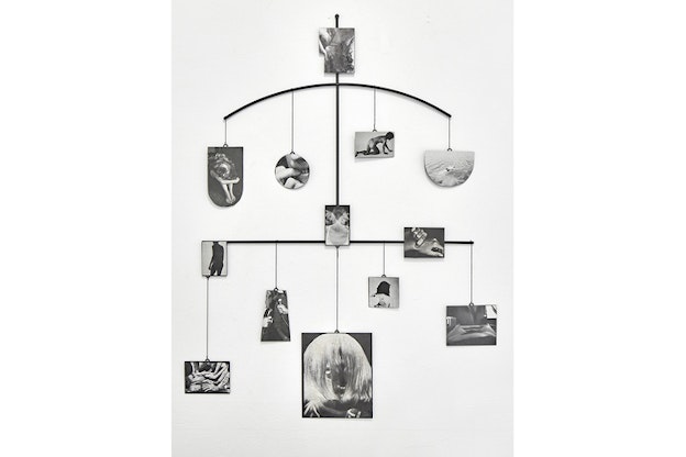 Pictures depicting various body parts hang from a steel structure's arch on the top and straight line on its bottom. 