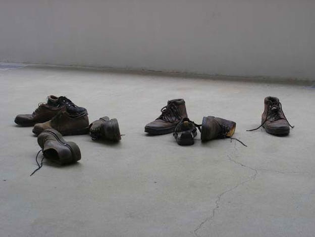 Multiple pairs of brown leather laced shows are randomly scattered on a white floor.