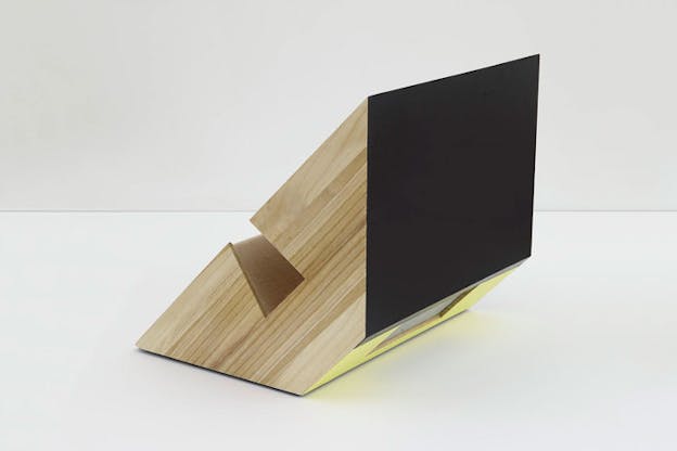 A wooden sculpture a black rectangular end and a gap in the middle. 