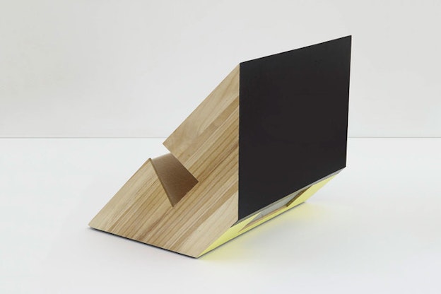 A wooden sculpture a black rectangular end and a gap in the middle. 