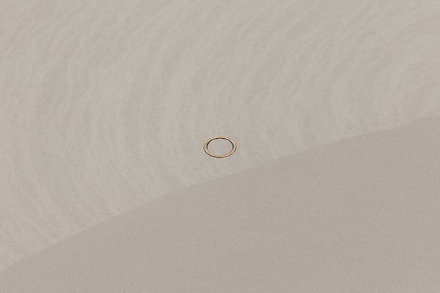 A golden ring sits on a white-gray surface.