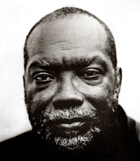 A black and white portrait of Fred Moten, staring at the camera with a graying beard.
