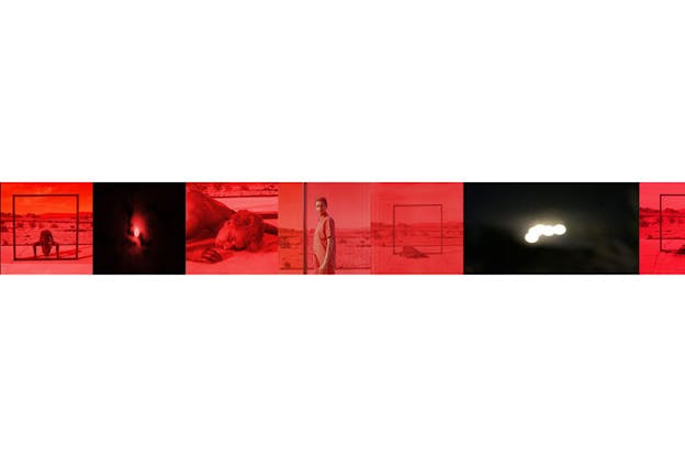 Collage of images resembling a red-hued film roll depict a person standing behind a large frame erected against a desert backdrop, a close-up of a person's face resting against concrete, and blurred white orbs evoking the sun and moon against a red and black sky.