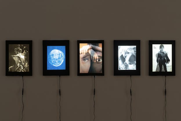 Five aligned lightboxes depicting figures, faces and the moon. Each has a straight cable at the bottom. 