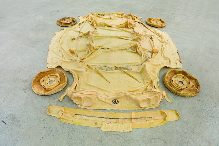 Yellow material cut out resembling a car is laid on the floor, four yellow deflated tires on each side.  