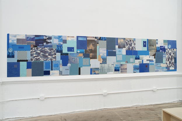 A panoramic collage of images with blue hues and undertones, on a wall.
