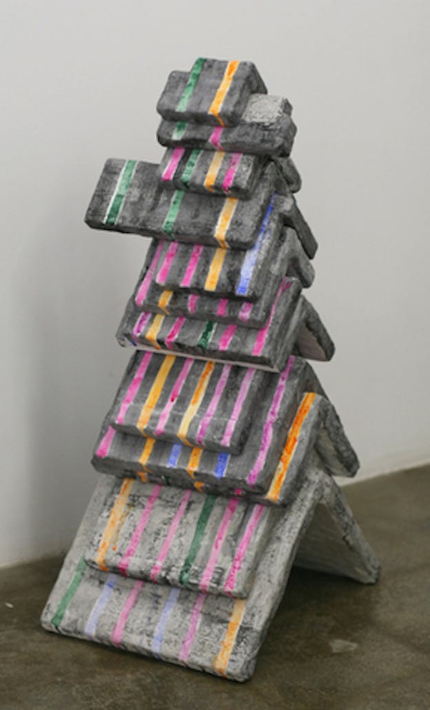 Stone gray sculpture of smaller chevron-shaped slabs layered atop larger slabs, painted with thin fuschia, orange, indigo, and green vertical lines. 