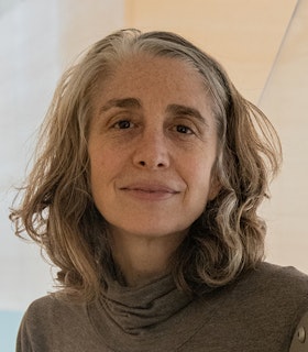 Portrait of Julianne Swartz with blond hair and dressed in a turtle neck smiling towards the camera.