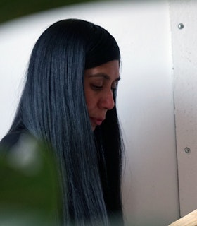 A profile of Carissa Rodriguez looking down and enveloped by her long black hair.