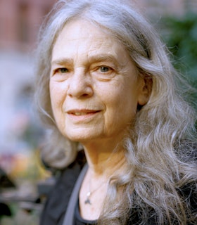 Portrait of Laurie Spiegel with long grey hair and a slight smile toward the camera.