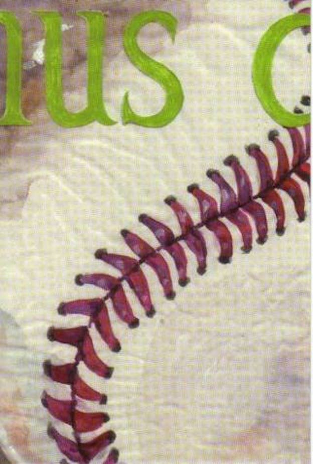A close up of a painted baseball and its red stitching. On the top, there is some green text which has gotten cut off leaving only 