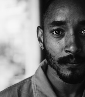 A black and white portrait of Niall Jones. The left side of his face is slightly hidden. He is wearing a collared shirt.