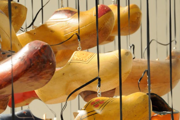 Close up image of wooden shoes in colors of yellow, red and blue hang from multiple ropes.