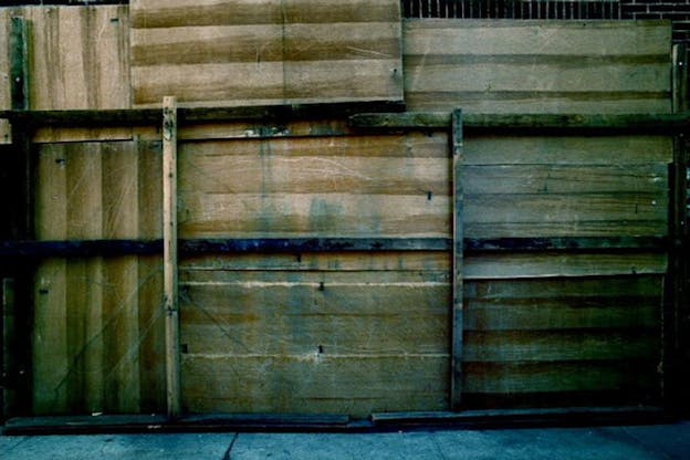 Dark-toned image of what appears to be stacked wooden crates on concrete. 