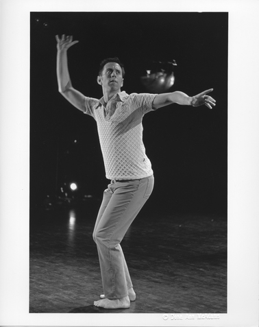 Image of a performer with bent knees and both arms open facing towards their left.