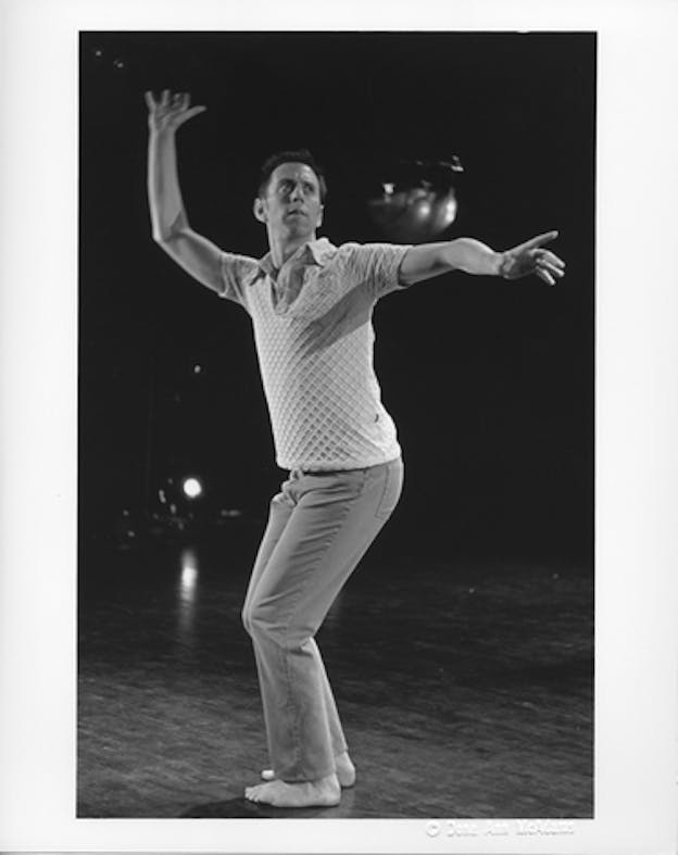 Image of a performer with bent knees and both arms open facing towards their left.