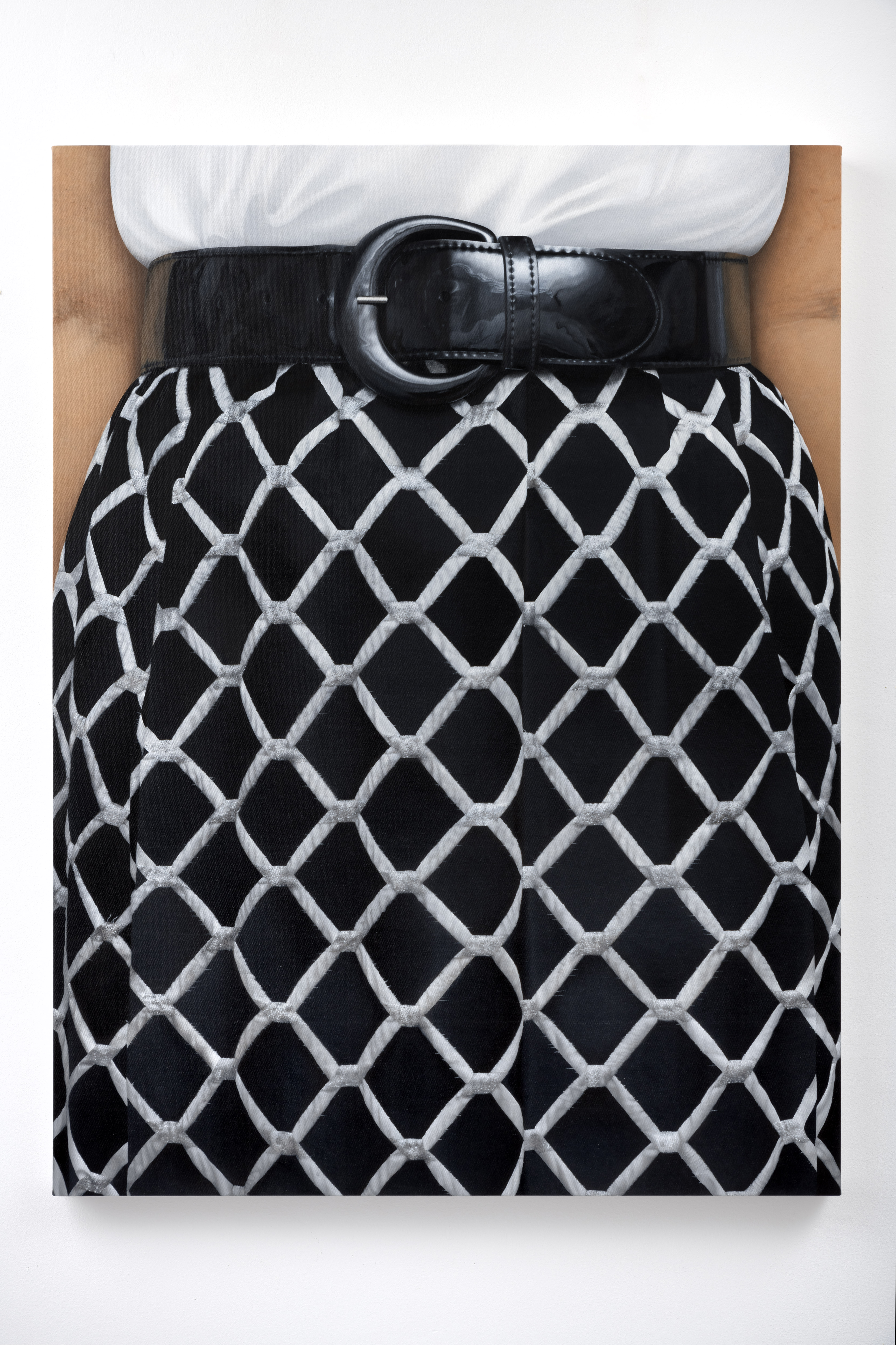 A photorealistic oil painting of a closeup view of a black skirt with white chain link pattern on a person, paired with a black patent leather belt. A small portion of a white blouse tucked into the belt is visible along with the inner ams of the person wearing the skirt.