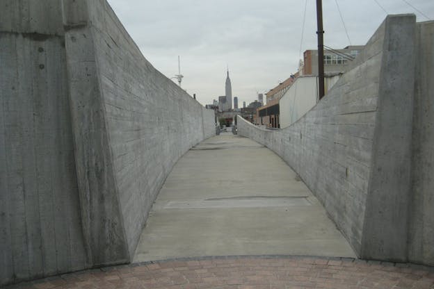 A cement road surrounded on each side by a gray wall.