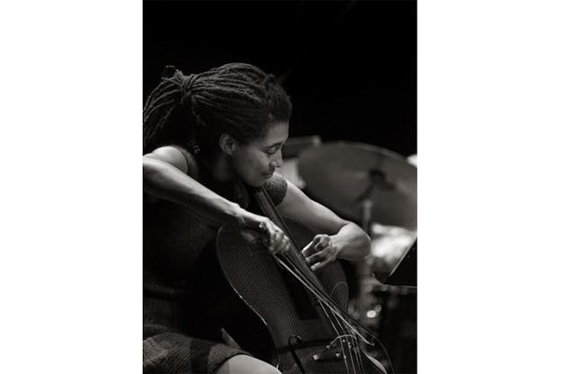 Black and white profile photograph of Tomeka Reid playing the cello and smiling. 