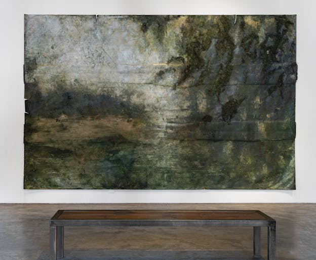 A rectangular painting with several intentionally torn edges. A hazy, abstract landscape image composed of dark, light, and yellowish green tones, along with lighter blue tones in the top left horizon area.